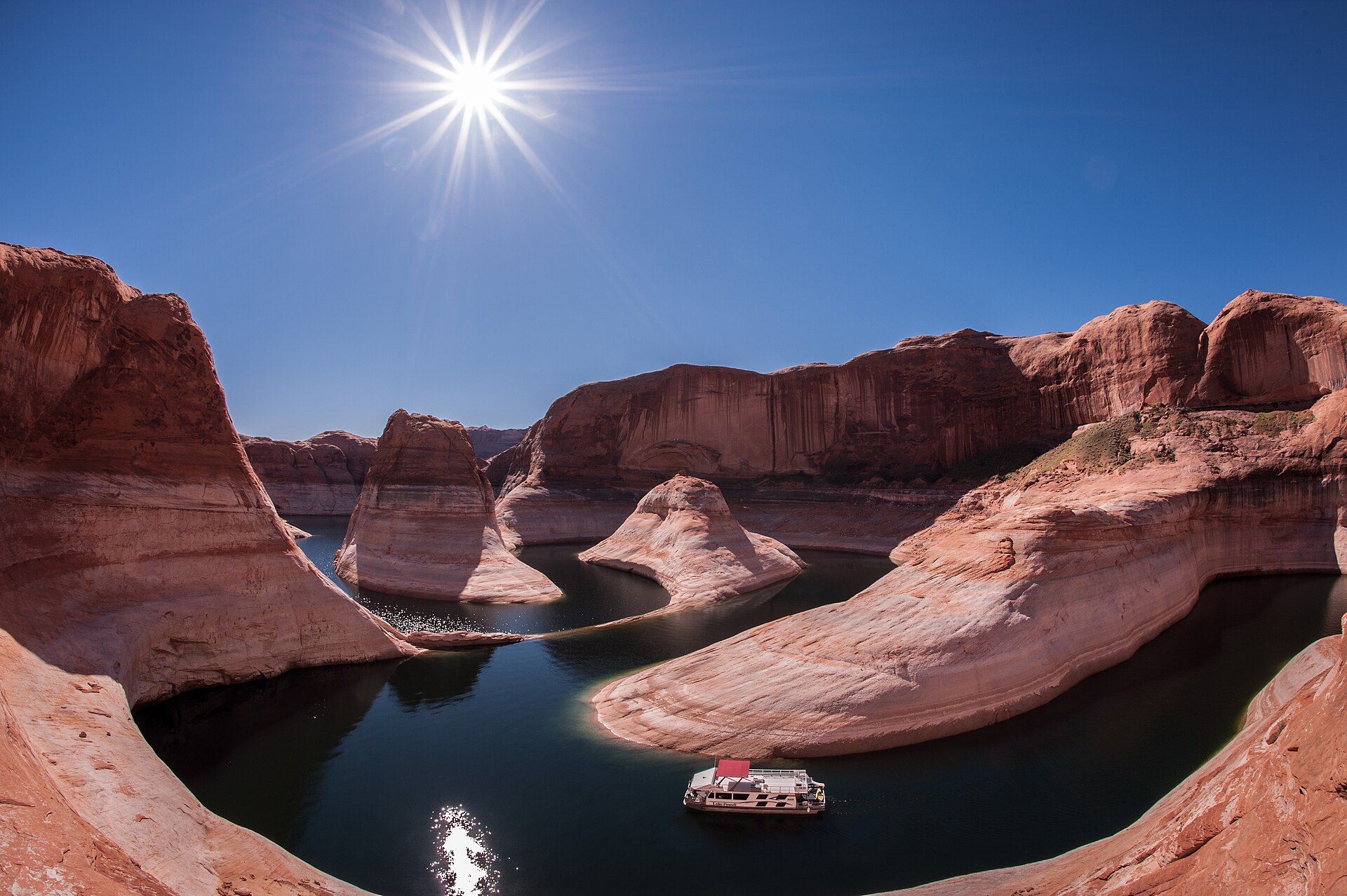 A houseboat in Reflection Canyon on Lake Powell, between red sandstone walls